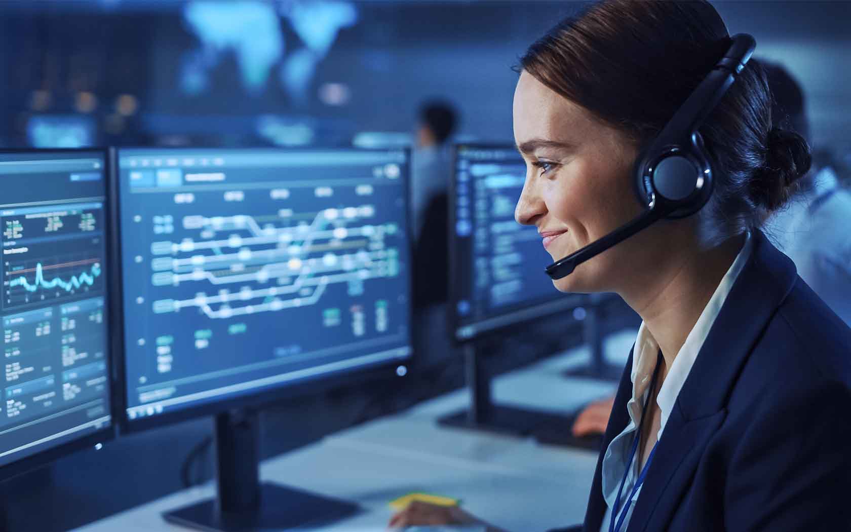 Woman with headset sitting in front of three computer screens